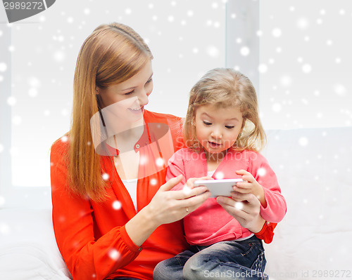 Image of happy mother and daughter with smartphone at home