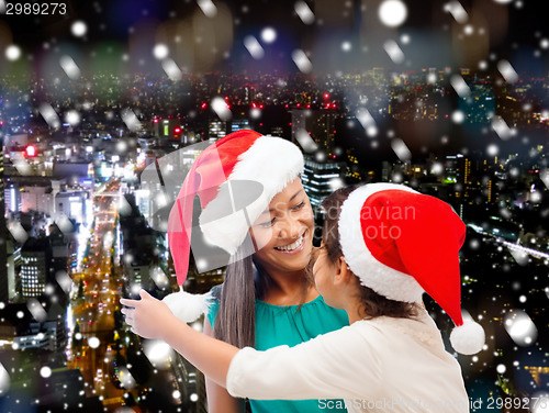 Image of happy mother and girl in santa hats