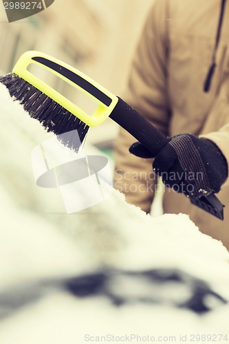 Image of closeup of man cleaning snow from car