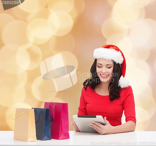 Image of smiling woman with shopping bags and tablet pc