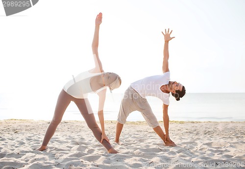 Image of couple making yoga exercises outdoors