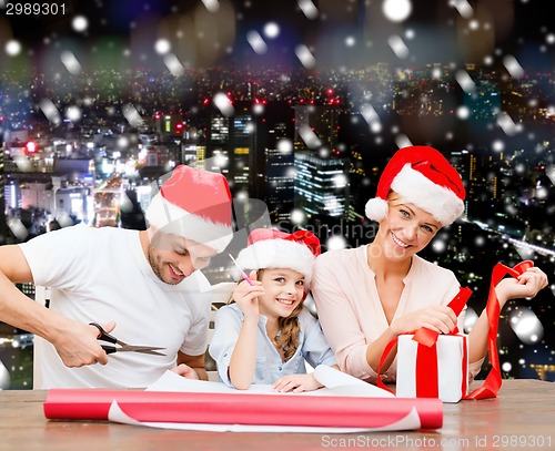 Image of happy family in santa helper hats packing gift