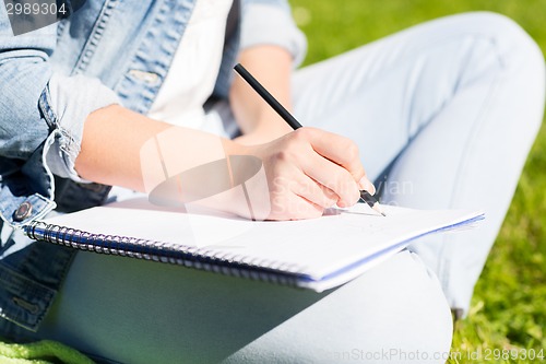 Image of close up of girl with notebook writing in park