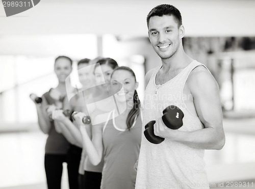 Image of group of smiling people with dumbbells in the gym