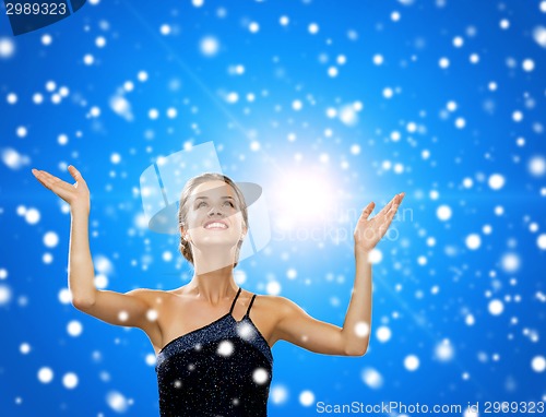 Image of smiling woman raising hands and looking up