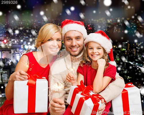 Image of happy family in santa helper hats with gift boxes