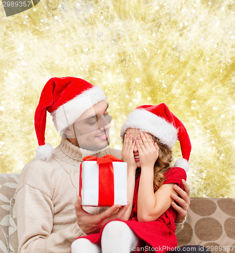 Image of smiling daughter waiting for present from father