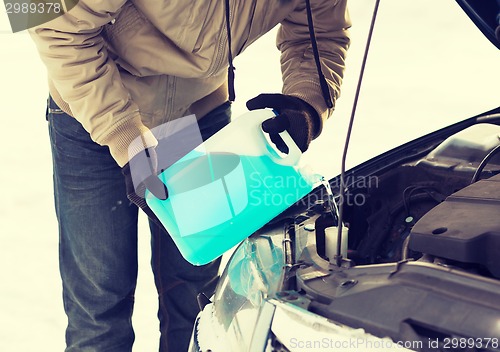 Image of closeup of man pouring antifreeze into water tank