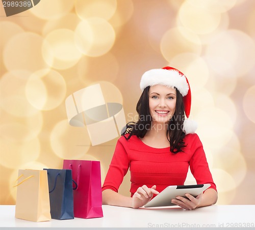 Image of smiling woman with shopping bags and tablet pc