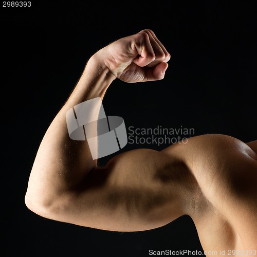 Image of close up of young man showing biceps