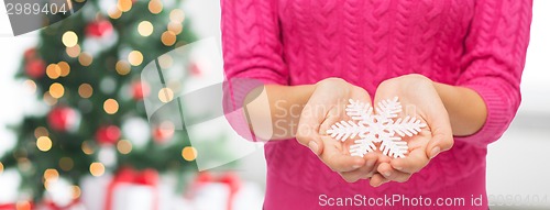 Image of close up of woman in sweater holding snowflake