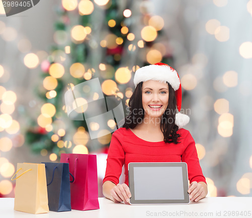 Image of smiling woman with shopping bags and tablet pc