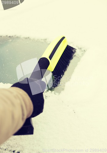 Image of closeup of man cleaning snow from car