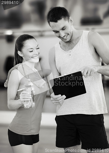 Image of smiling male trainer with woman in the gym