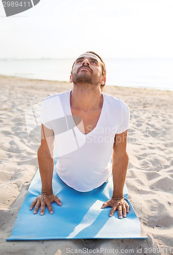 Image of man doing yoga exercises outdoors