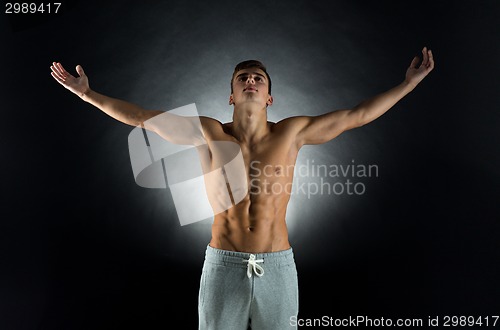 Image of young male bodybuilder with raised hands