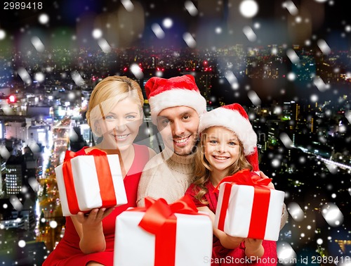 Image of happy family in santa helper hats with gift boxes