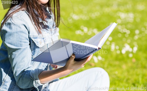 Image of close up of smiling young girl with book in park