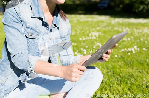 Image of close up of girl with tablet pc sitting on grass