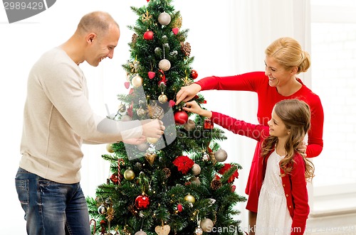 Image of smiling family decorating christmas tree at home