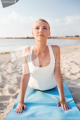 Image of young woman making yoga exercises outdoors