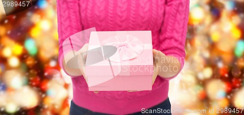 Image of close up of woman in pink sweater holding gift box