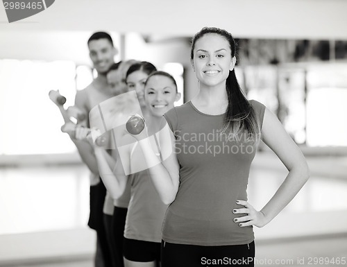 Image of group of smiling people with dumbbells in the gym