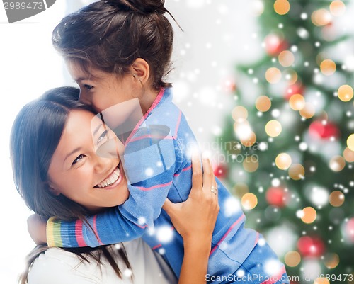 Image of smiling little girl and mother hugging indoors