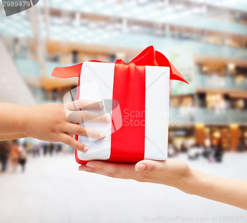 Image of close up of child and mother hands with gift box