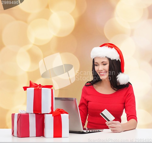 Image of smiling woman with gifts, laptop and credit card