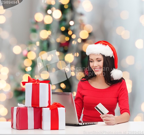 Image of smiling woman with gifts, laptop and credit card