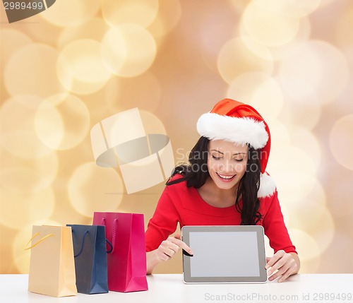 Image of smiling woman with shopping bags and tablet pc