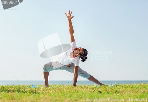 Image of smiling man making yoga exercises outdoors