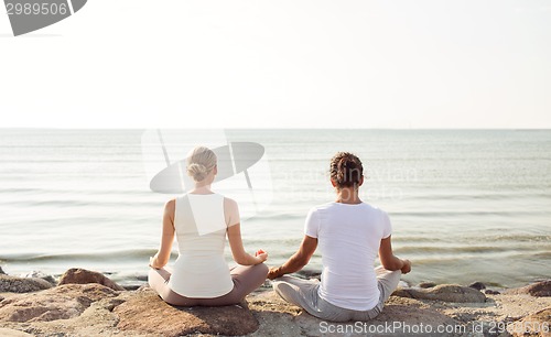 Image of couple making yoga exercises outdoors