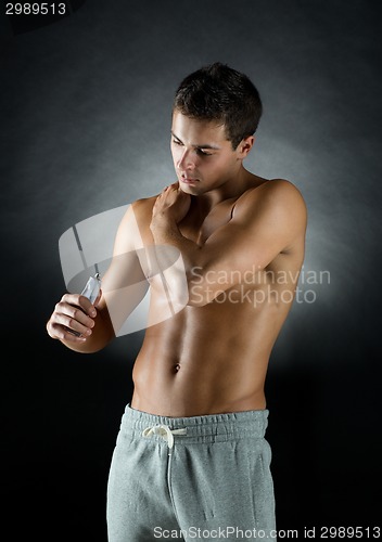 Image of young male bodybuilder applying pain relief gel