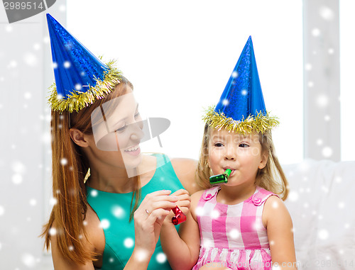 Image of mother and daughter in party hats with favor horns