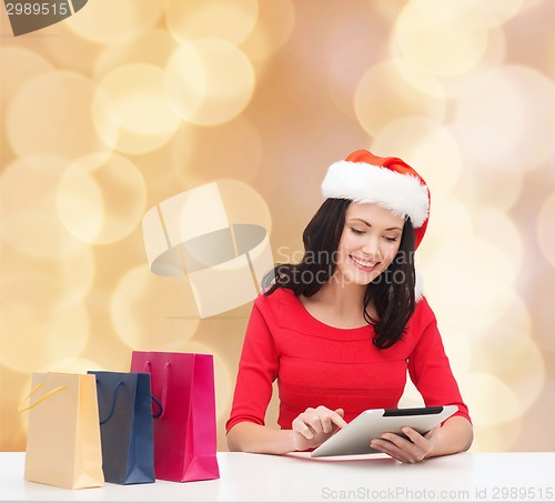 Image of smiling woman with shopping bags and tablet pc