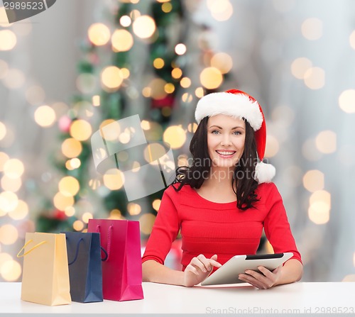 Image of smiling woman with shopping bags and tablet pc