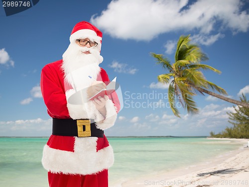 Image of man in costume of santa claus with notepad