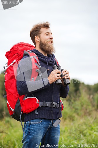 Image of smiling man with backpack and binocular outdoors