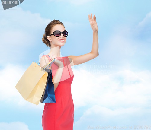Image of smiling elegant woman in dress with shopping bags