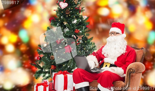 Image of man in costume of santa claus with laptop