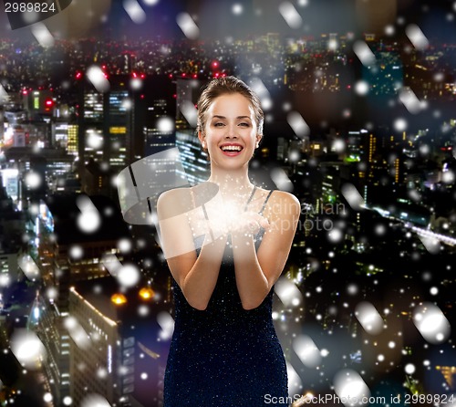 Image of laughing woman in evening dress holding something