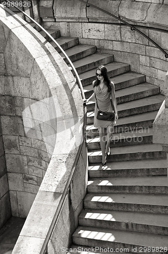 Image of woman in sunglasses and dress walking down stairs
