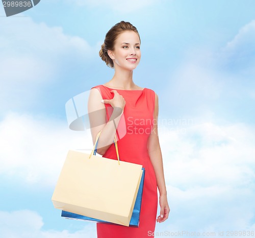 Image of smiling elegant woman in dress with shopping bags