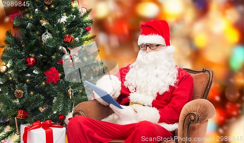 Image of man in costume of santa claus with tablet pc