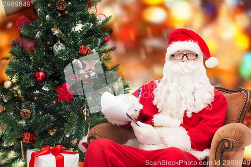 Image of man in costume of santa claus with notepad