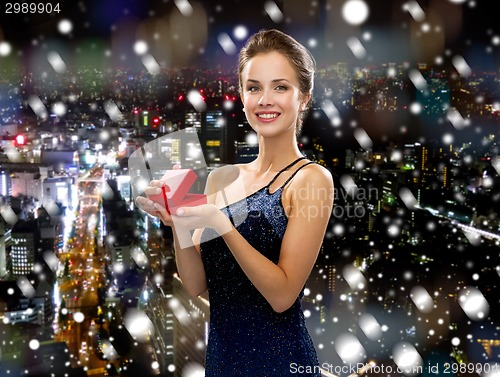 Image of smiling woman in evening dress with gift box