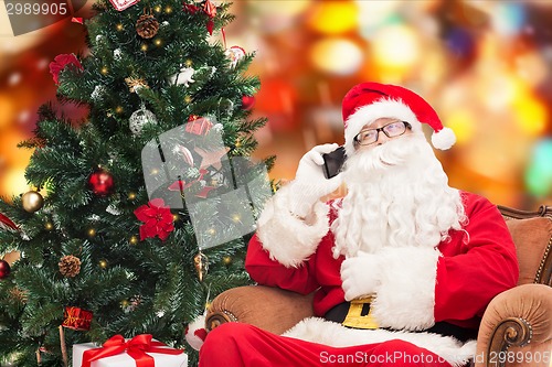 Image of santa claus with smartphone and christmas tree