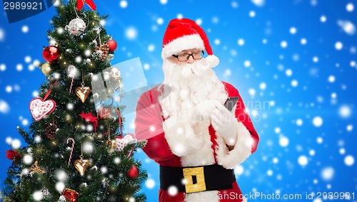 Image of santa claus with smartphone and christmas tree